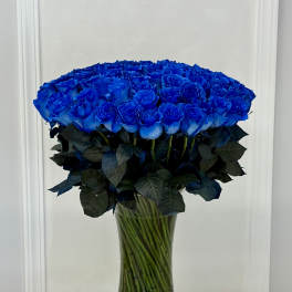 Large bouquet of vivid blue roses in a clear glass vase