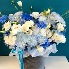 Blue and white floral arrangement in a gray hatbox with ribbon