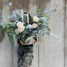Large winter floral arrangement with white roses and candles in a container