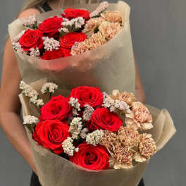 Two bouquets of red roses and peach carnations wrapped in brown paper