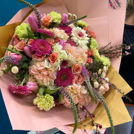 Large bouquet of pink, peach, and lime flowers wrapped in pastel paper