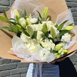 Large bouquet of white lilies and carnations wrapped in kraft paper
