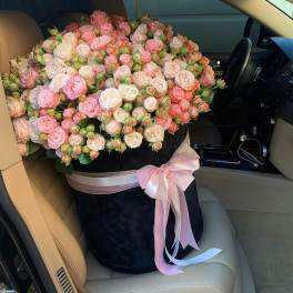 Large bouquet of pink and white roses in a black hat box with a pink ribbon