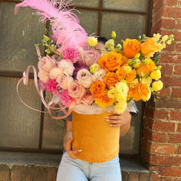 Large bouquet of pink, orange, and yellow roses in a velvet hatbox