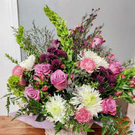 Basket arrangement of pink roses, white daisies, and purple flowers