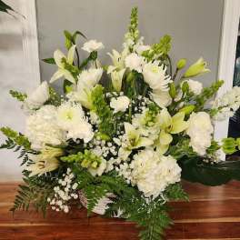 White floral arrangement with lilies, chrysanthemums, and carnations in a basket