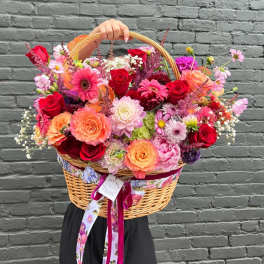 Large wicker basket filled with colorful mixed flowers and ribbon