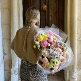 Person holding a large pastel bouquet of mixed flowers