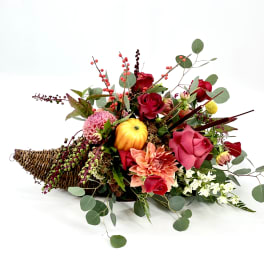 Low floral arrangement with red and pink blooms in a wicker basket