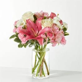 Pink lilies and roses arranged in a clear glass vase