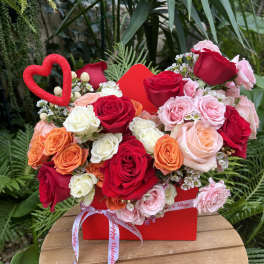 Heart-shaped rose arrangement in a red box with a ribbon