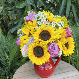 Bouquet of sunflowers and roses in a red pitcher vase