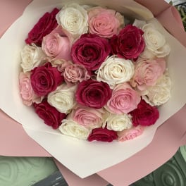 Bouquet of pink, white, and red roses wrapped in blush paper