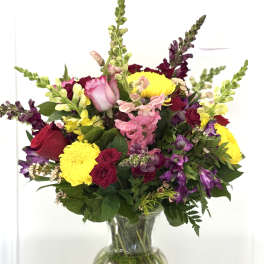 Mixed bouquet of roses, snapdragons, and chrysanthemums in a glass vase