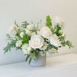 White rose bouquet in a gray vase with green accents