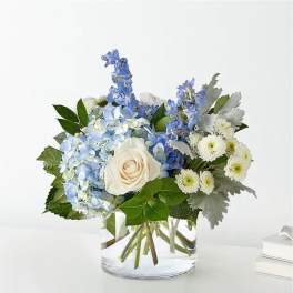 Blue hydrangeas and white roses in a clear glass vase