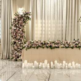 Wedding floral arch and table garland with candles in a ballroom