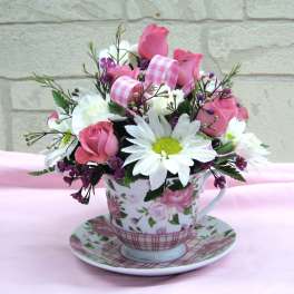 Pink and white flower arrangement in a floral teacup and saucer