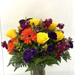 Bouquet of yellow, purple, and orange flowers in a clear glass vase