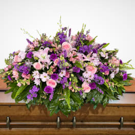 Large pink and purple floral spray on a wooden casket