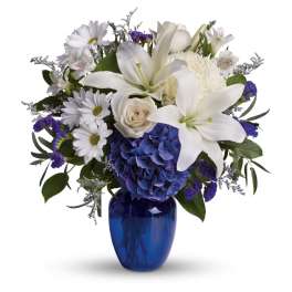 White lilies and daisies with blue hydrangea in a cobalt vase