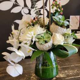 White flowers and succulents arranged in a glass vase