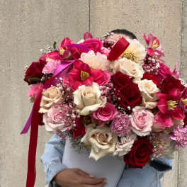 Large bouquet of red, pink, and cream roses in a white hatbox