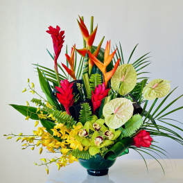 Tropical flower arrangement in a dark vase with red, orange, yellow, and green blooms