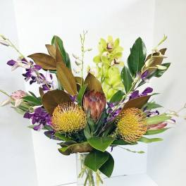 Tropical bouquet with orchids and protea in a clear glass vase