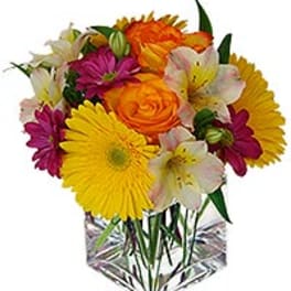 Mixed bouquet of daisies, roses, and lilies in a clear vase