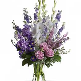Purple and white bouquet with roses and tall spikes in a clear vase