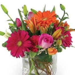 Bright mixed bouquet in a clear square vase