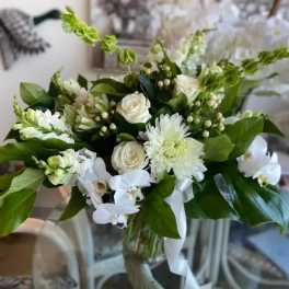 White floral bouquet with roses, orchids, and chrysanthemums in a glass vase