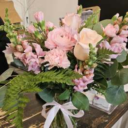 Pink and peach bouquet in a glass vase with a white ribbon