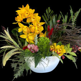 Yellow orchids in a white bowl with mixed tropical foliage
