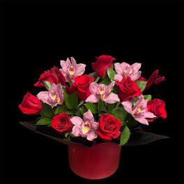 Red roses and pink orchids arranged in a red box