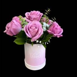 Pink roses arranged in a pastel pink box with greenery