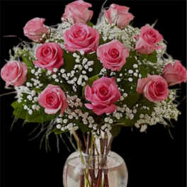 Pink roses arranged in a clear glass vase with white baby's breath