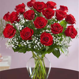 Red roses arranged in a clear glass vase with white baby's breath