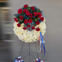 Standing floral wreath with red roses and white flowers on an easel