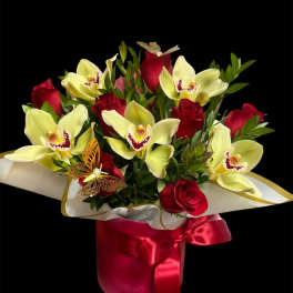 Bouquet of red roses and pale yellow orchids in a red ribboned wrap