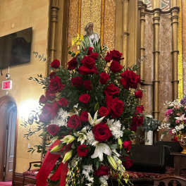 Tall red rose and white lily arrangement with a red ribbon