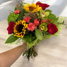 Bouquet of red roses, sunflowers, and pink carnations with green accents
