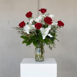 Red roses and white lilies arranged in a clear glass vase