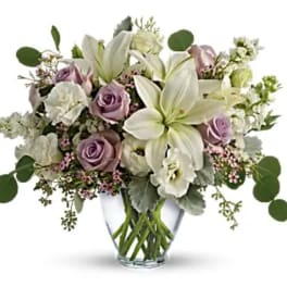 Bouquet of white lilies and lavender roses in a clear glass vase