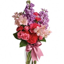 Pink and purple mixed bouquet in a clear glass vase with a satin ribbon
