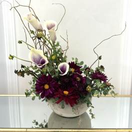 Purple calla lilies and dark dahlias in a white bowl vase