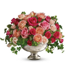 Pink and peach roses arranged in a silver pedestal vase