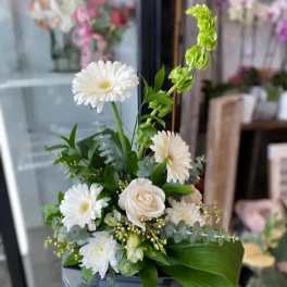 White gerbera daisies and a white rose in a vase with green accents