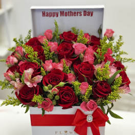 Red and pink roses in a gift box with chocolates and a red bow